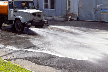 Water truck watering the asphalt at a manufacturing plant for du