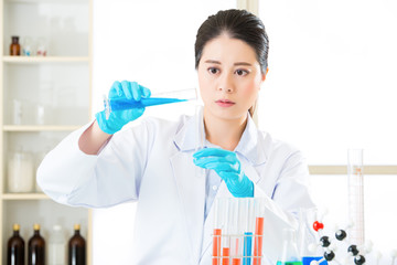 Young asian scientist pipetting in life science laboratory