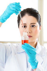 Fototapeta premium Asian female scientist mixing chemical substances for medical