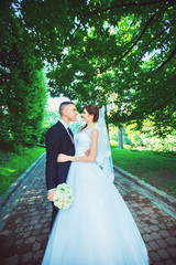 beautiful wedding couple. The bride and groom in wedding day walking outdoors in spring nature. Bridal couple Newlywed happy woman and man embracing a green park.