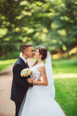 the newly married couple kissing at alley in park