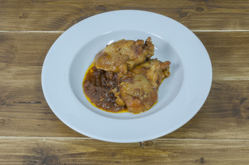 Roasted chicken with gravy in white plate on wood table