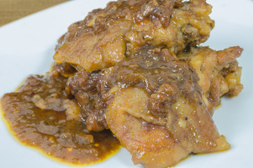 Roasted chicken with gravy in white plate on wood table