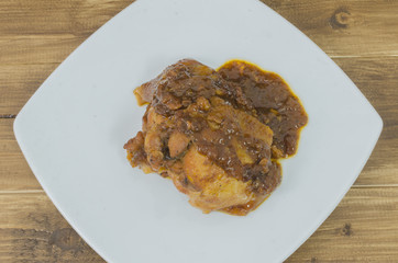 Roasted chicken with gravy in white plate on wood table