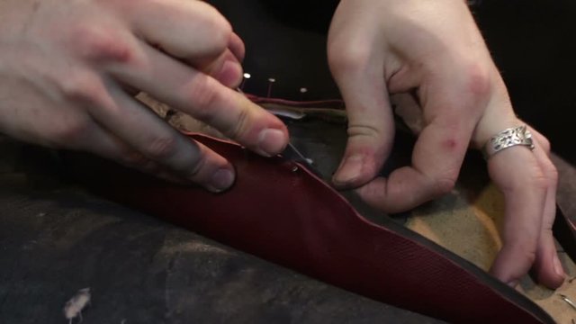 Shoemaker sews shoes. Cut leather