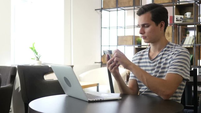 Young man using smart phone and notebook
