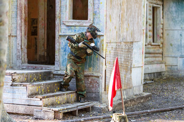 Young man in extreme paintball training with capturing flags.