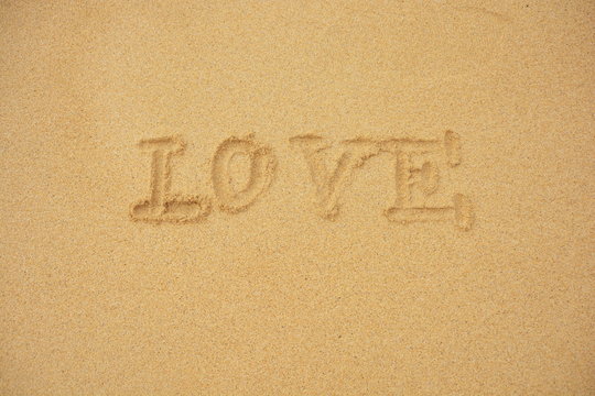 Love You und Herz in den sonnigen Strandsand geschrieben 