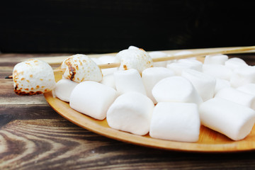 Fluffy white marshmallow in wooden bowl on old wooden table