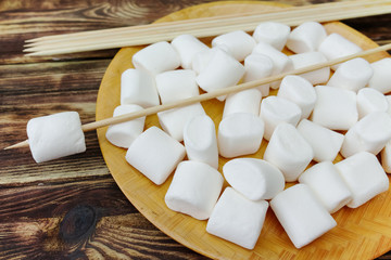 Fluffy white marshmallow in wooden bowl on old wooden table