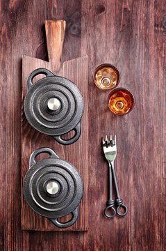 The small cast iron pan with forks and glasses on a cutting board