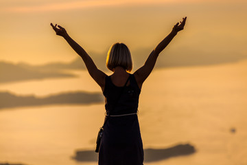 Fototapeta premium Female tourist standing on the background of Bay at sunset. Misty layers of islands. Sunset in Adriatic sea with layers mountains on the horizon. Hills, growing out of the water. Dubrovnik. Croatia.