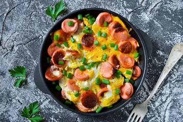 The dish for breakfast - scrambled eggs with sausage and green o - obrazy, fototapety, plakaty