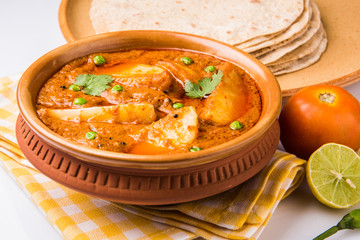 potato curry or aalu masala or aaloo masala with green peas, served with indian bread / roti / chapati / naan / fulka / phulka