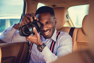 A black man using dslr camera in a car.