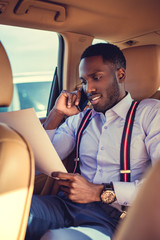 Black man using smartphone in a car.