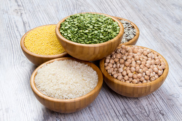 Set of cereals, peas, rice, millet, chickpeas sprinkled in bamboo bowls on wooden background