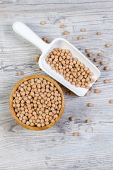 Walnut chickpeas in a bamboo bowl with a shovel on a white wooden background