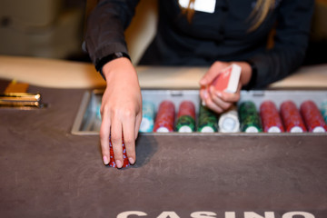 Closeup of hands of dealer with chips and cards in casino, selec