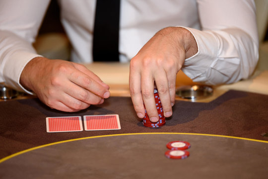 Closeup of hands of poker player with chips on poker table, sele