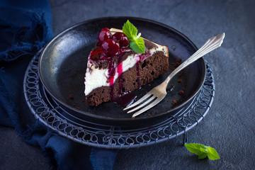 Piece of cheesecake brownie cake with cherry sauce