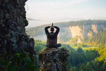 Man sitting on the top of the mountain in yoga pose