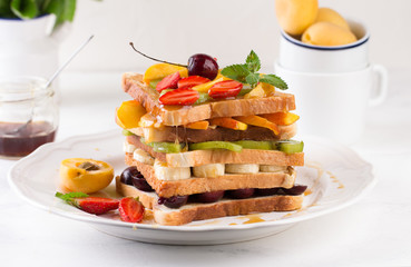 Stack of French toast with fresh strawberries, peaches, cherry, kiwi and banana