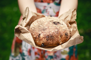 Close up of hands holding rustic bread packed in paper. Photo with shallow depth of field.