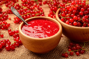 Red currants jam in wooden bowl.