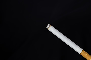 Burning cigarette with smoke on black background