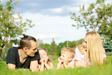 Fototapeta premium Portrait of happy parents with kids lying at the park