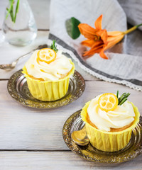Cupcakes with cream cheese on white wooden table.