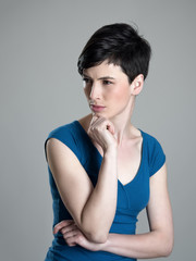 Unhappy short hair beauty looking away squinting eyes over gray studio background
