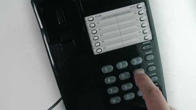 Hand picks up the black (white) phone, dials a number and hangs up