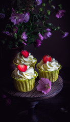 Cupcakes with strawberry on dark wooden table.