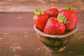 Ripe fresh juicy organic strawberries in old clay bowl