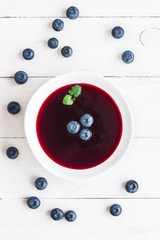 blueberry soup on wooden white background, top view, flat lay