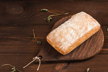 Bread ciabatta with herbs on wooden background