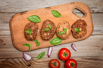  Fried pork burgers with tomatoes on the wooden board, top view