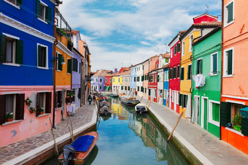 multicolored bright houses over canal with boats of Burano island, Venice, Italy