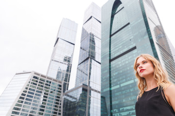 Fototapeta premium Modern skyscrapers and portrait of young attractive businesswoman