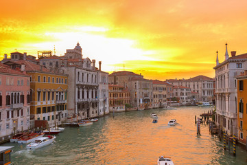 Fototapeta na wymiar muticolored Venice houses over water of Grand canal at bright orange sunset, Italy