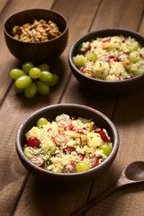 Couscoussalat mit Weintrauben, Granatapfel, Walnüsse, Käse, Zitronensaft und frische Minze, fotografiert mit natürlichem Licht (Selektiver Fokus, Fokus in die Mitte des ersten Salats)