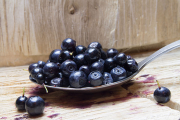 Bilberry. Blueberries on spoon and wooden background.