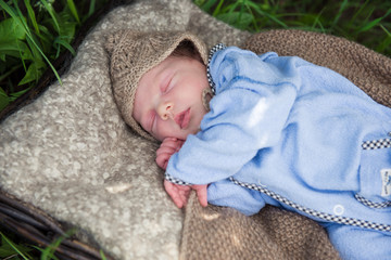 newborn baby in blue suit sleeping in the garden