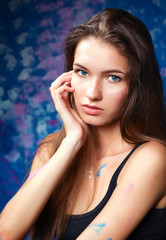 Fototapeta premium Young woman sitting near painting wall