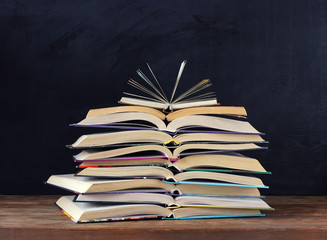 Stack of open books, school blackboard. Back to school.