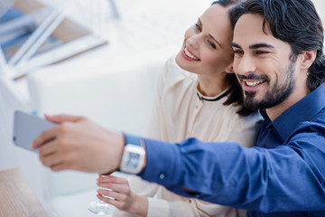 Obraz premium Cheerful lovers photographing themselves on smartphone