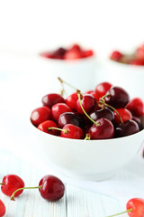 Ripe cherries in bowl on a white wooden table