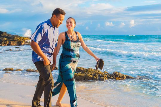 Pregnant young woman expecting baby with father on beach in tropical paradise.